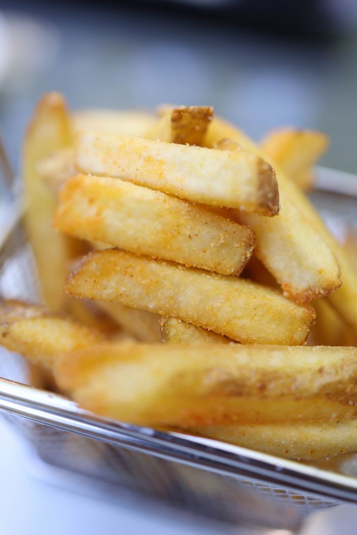 Appetizing close-up of crispy golden French fries in a metal basket.