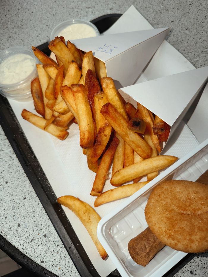 Tasty french fries served on a tray with sauces and croquettes.