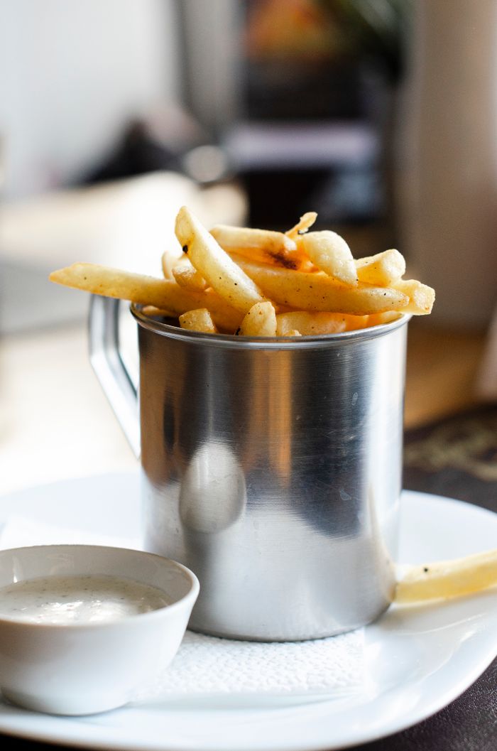 Tasty french fries served in a sleek steel cup with a side dipping sauce, perfect for a quick snack.
